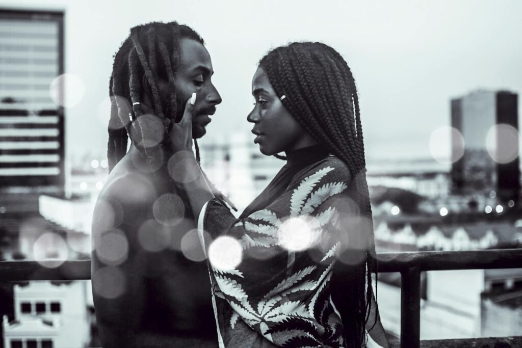 A romantic black and white photo of a couple embracing on a city rooftop with bokeh effect. - black love